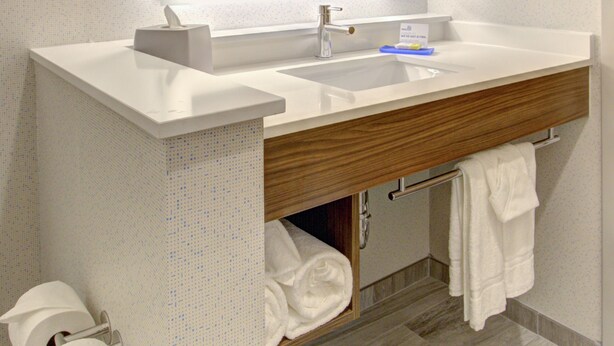 Ein modernes Badezimmer mit großem Spiegel, weißem Waschbecken und Holz-Badmöbel.