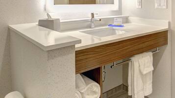 Une salle de bain moderne avec un grand miroir, un lavabo blanc et un meuble-lavabo en bois.
