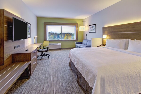A hotel room with a bed, desk, chair, TV, and a window with a view of trees. - Holiday Inn Express & Suites Charlotte Southwest by IHG (Charlotte)