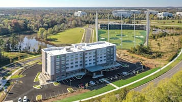 A hotel with a parking lot and a golf course in the background.