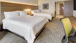 Ein Hotelzimmer mit zwei Betten, einem Schreibtisch und einem Stuhl.