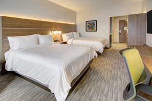 A hotel room with two beds, a desk, and a chair.