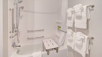 Un baño moderno con bañera, ducha y barras de apoyo.