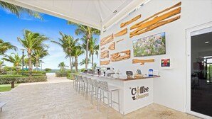 Ein Strandcafé mit weißem Tresen, Barhocker und Holzverkleidung an den Wänden.