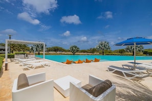Relax by the serene pool surrounded by a sandy deck and lounge chairs.