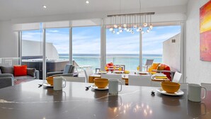 A modern dining area with a large table, chairs, and a view of the sea. - Aruba Family Friendly Oceanview PH with Hot Tub (Eagle Beach)