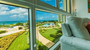 A room with a large window overlooking a well-maintained lawn, a pool, and a building complex.