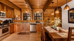 A wooden cabin kitchen with a central island, stainless steel appliances, and pendant lighting.