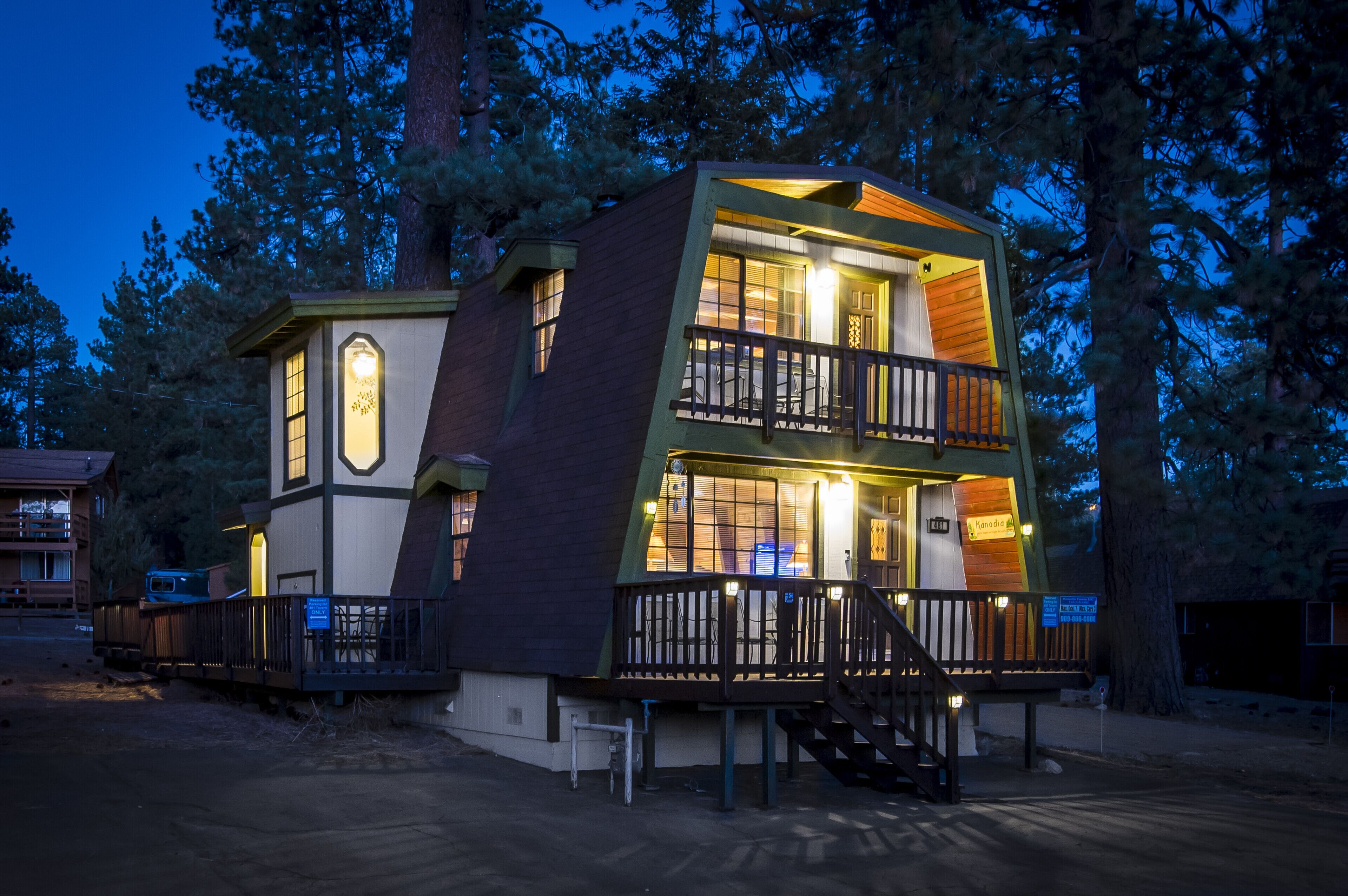 Une cabane en bois à deux étages, dotée d’un balcon et entourée d’arbres.