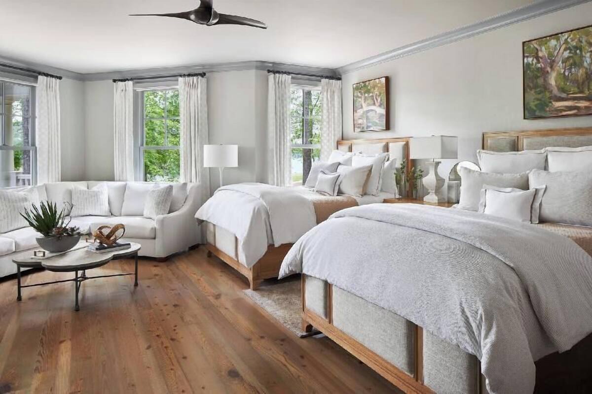 A bedroom with a large bed, a sofa, a bedside table, and a window with curtains.