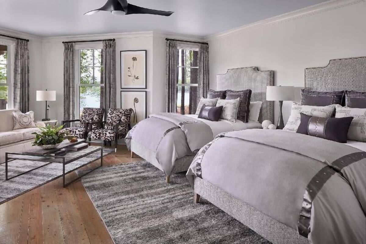 A bedroom with two beds, a sofa, a coffee table, and a large window with curtains.