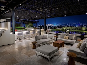 A rooftop bar with outdoor seating, a city view, and a modern architectural design.