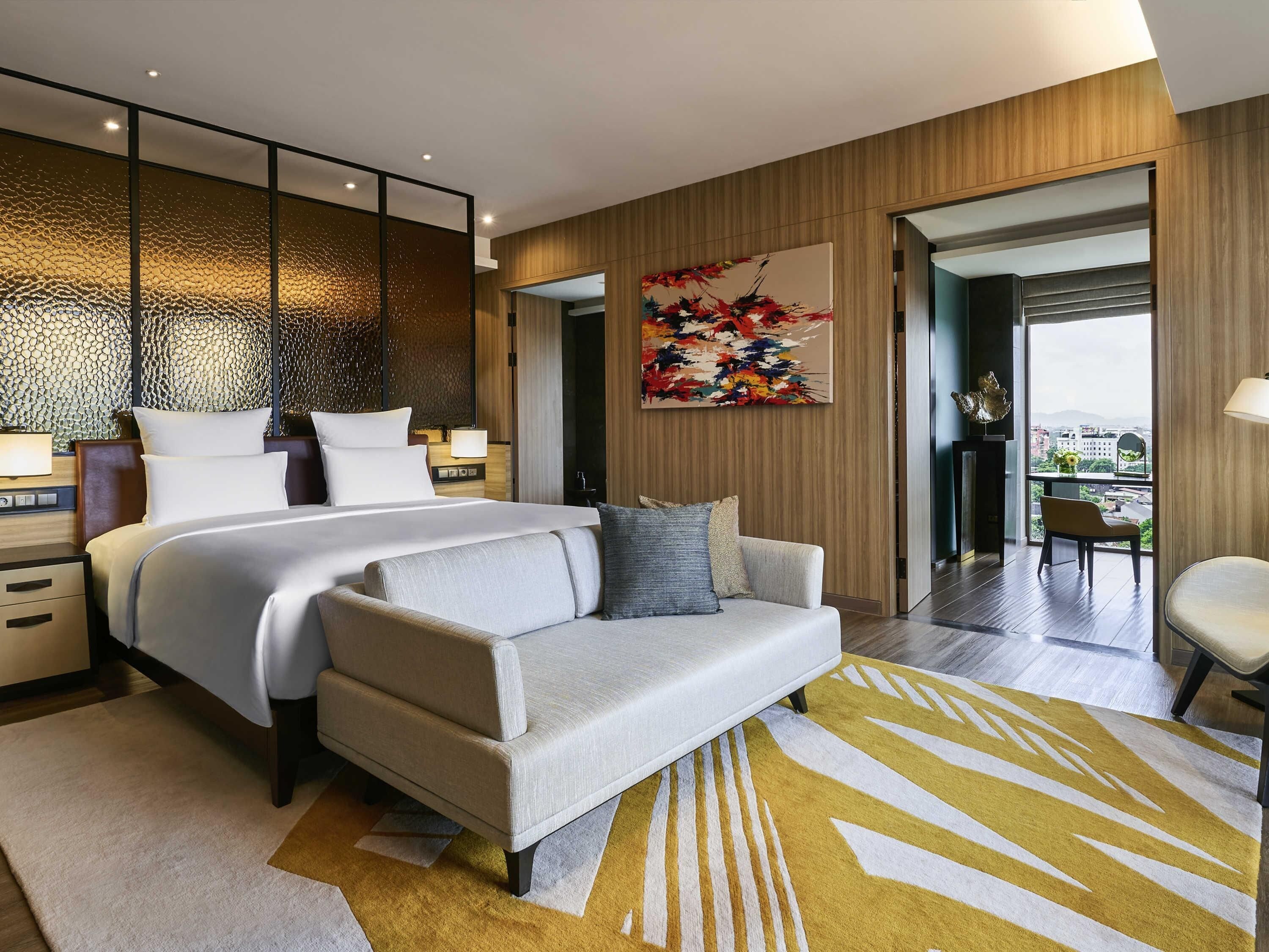 Une chambre d’hôtel moderne dotée d’un grand lit, d’un canapé, d’un coin repas et offrant une vue sur la ville.