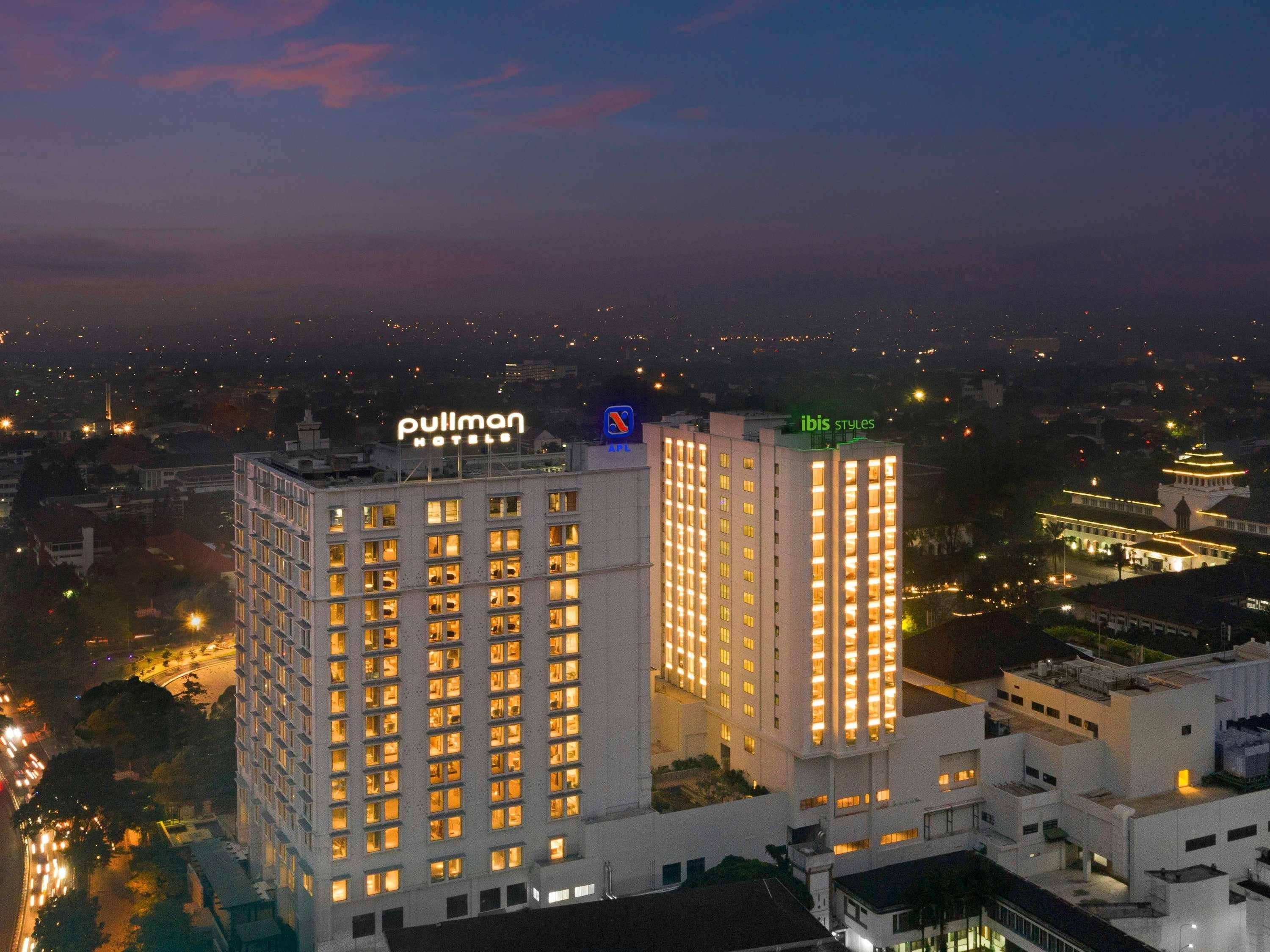 A hotel with multiple floors, a prominent sign for 'Pulmon Hotels,' and another sign for 'Ibis Styles.'