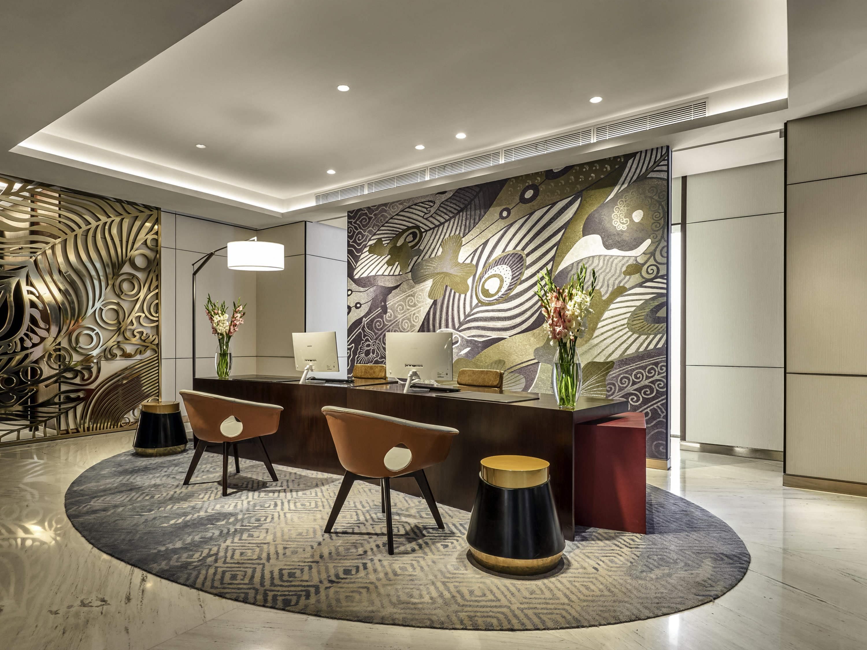 A modern reception area with a central desk, two chairs, and a decorative wall.