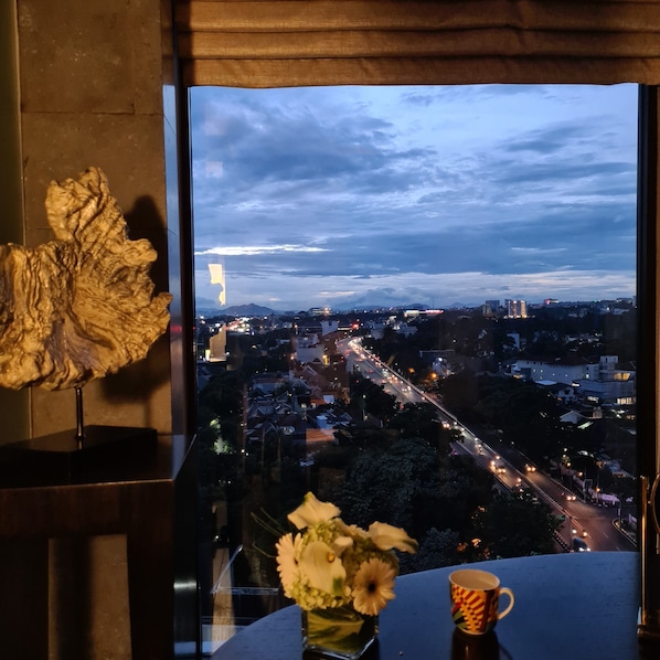 A cityscape view from a window with a decorative piece on the left and a vase with flowers on the right. - Pullman Bandung Grand Central (Bandung)