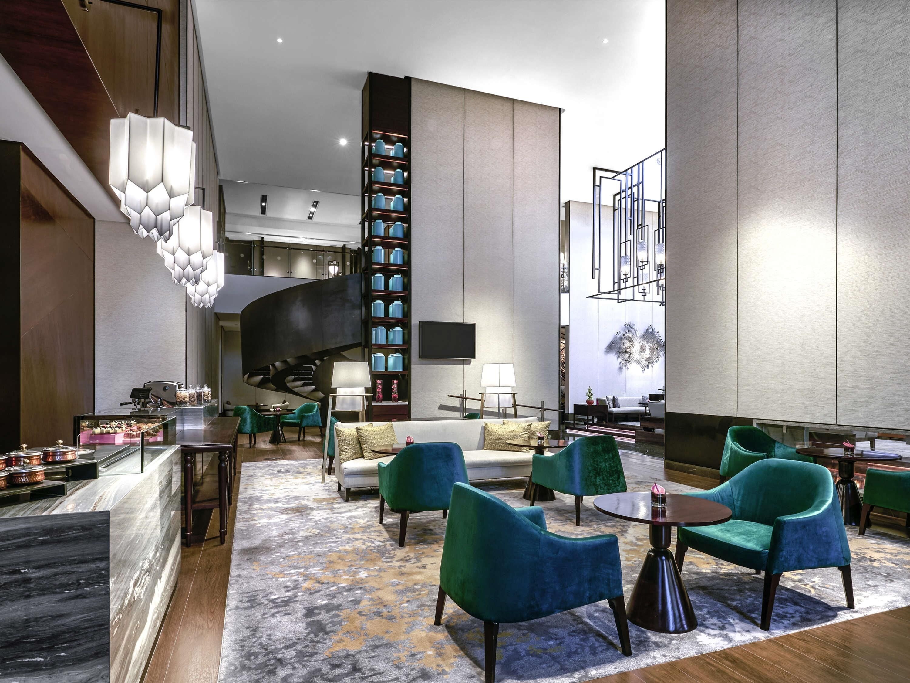 Un hall d’hôtel moderne avec un escalier en colimaçon, un espace salon et un mur décoratif.