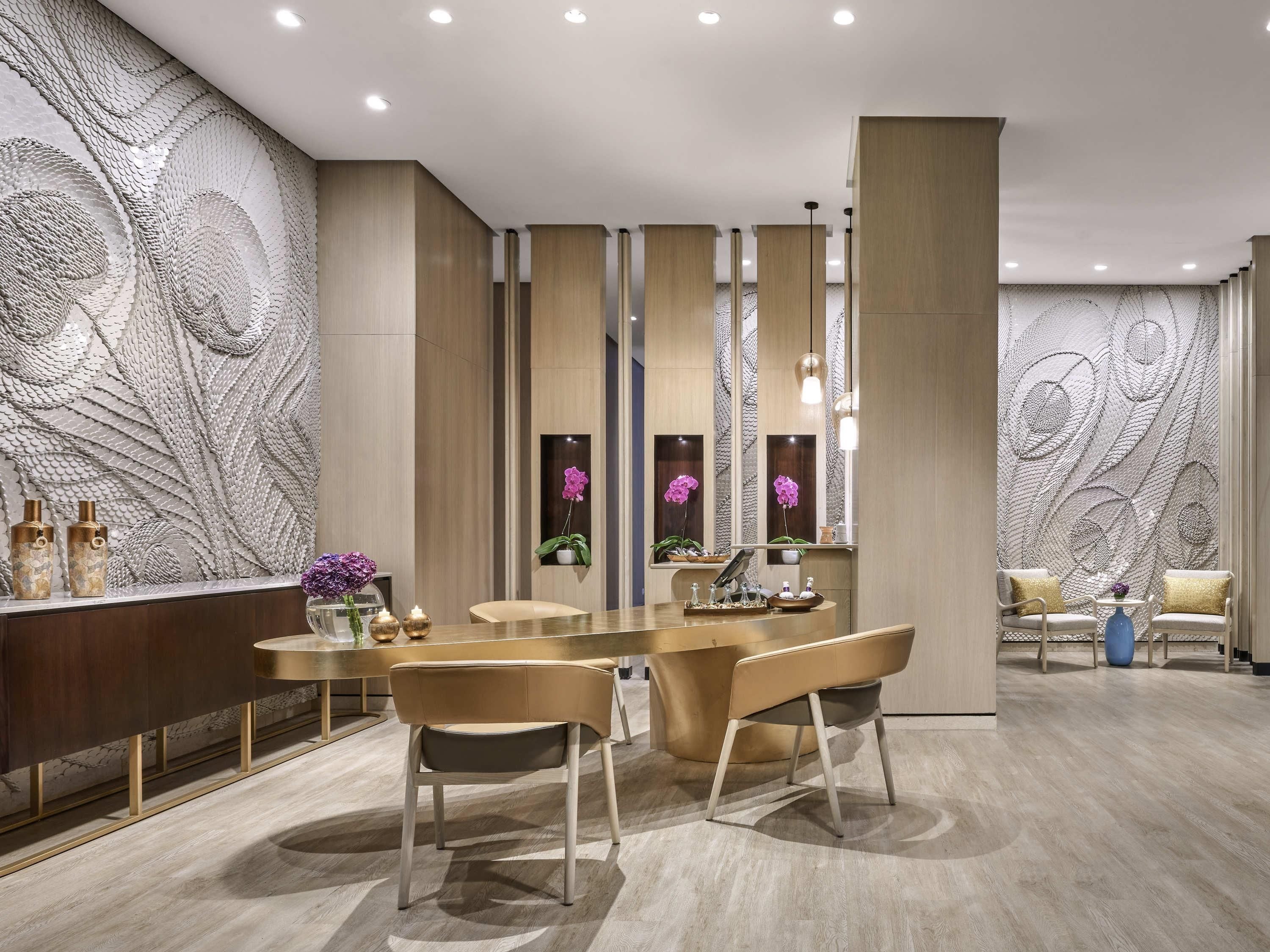 A modern dining area with a central round table, two chairs, and a decorative wall with peacock feather patterns.