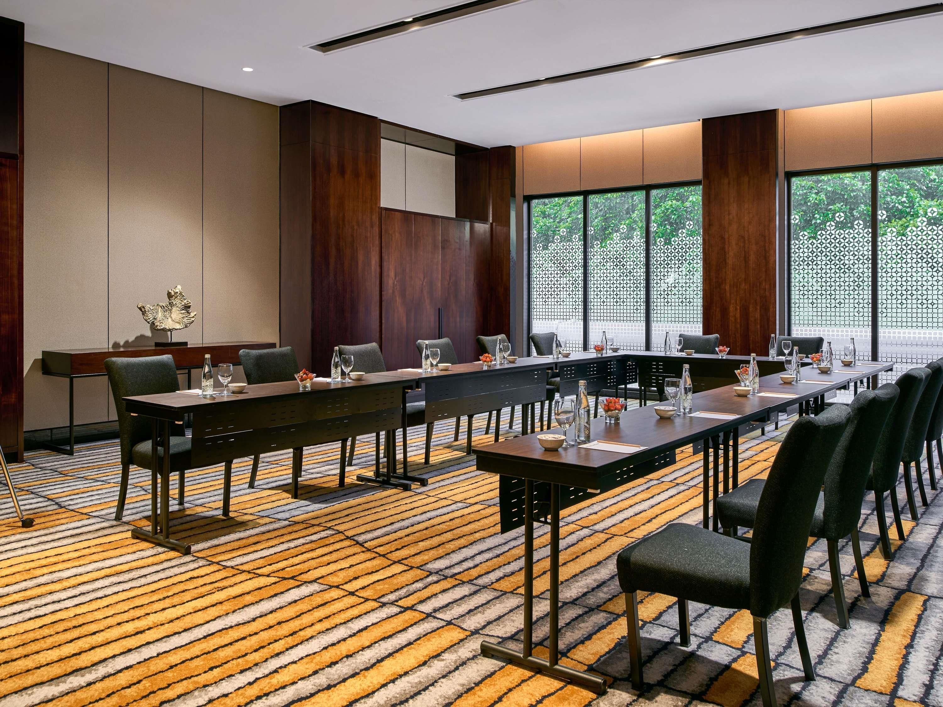 Une salle de conférence avec une longue table, des chaises et un tapis à motifs.