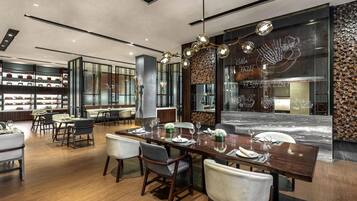 A modern dining area with a long wooden table, chairs, and a decorative wall with a fireplace.