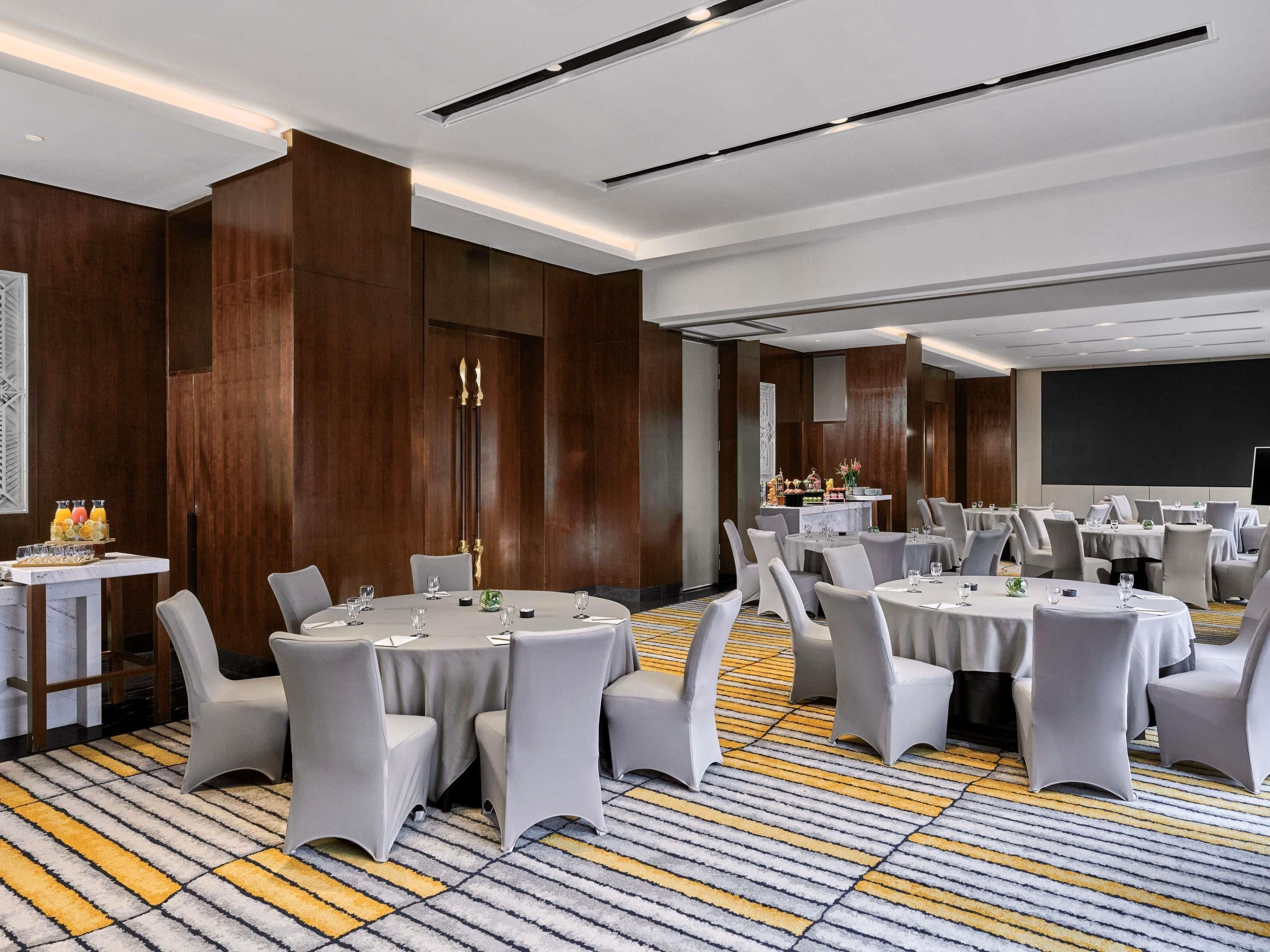 A conference room with round tables, chairs, and a projector screen.