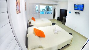 A hotel room with two beds, a TV mounted on the wall, and a view of the outdoors through the window. - Hotel Molino De Viento (San Andrés)