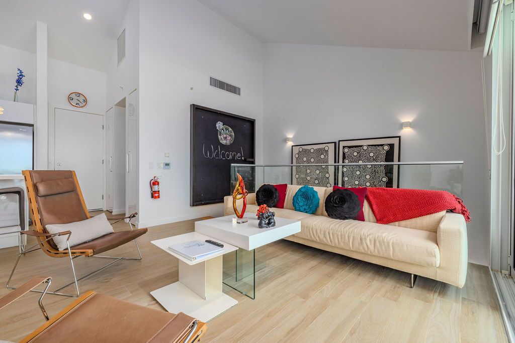Uma sala de estar moderna com um sofá, uma mesa de centro de vidro, uma poltrona de couro e uma lareira.