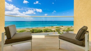 Een balkon met twee stoelen, uitkijkend op het strand.