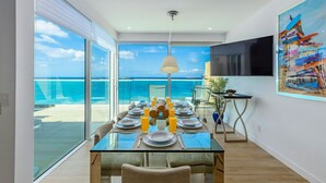 Een eethoek met een glazen tafel, stoelen en uitzicht op de oceaan.