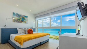Een moderne slaapkamer met een groot bed, een bureau en uitzicht op de oceaan.
