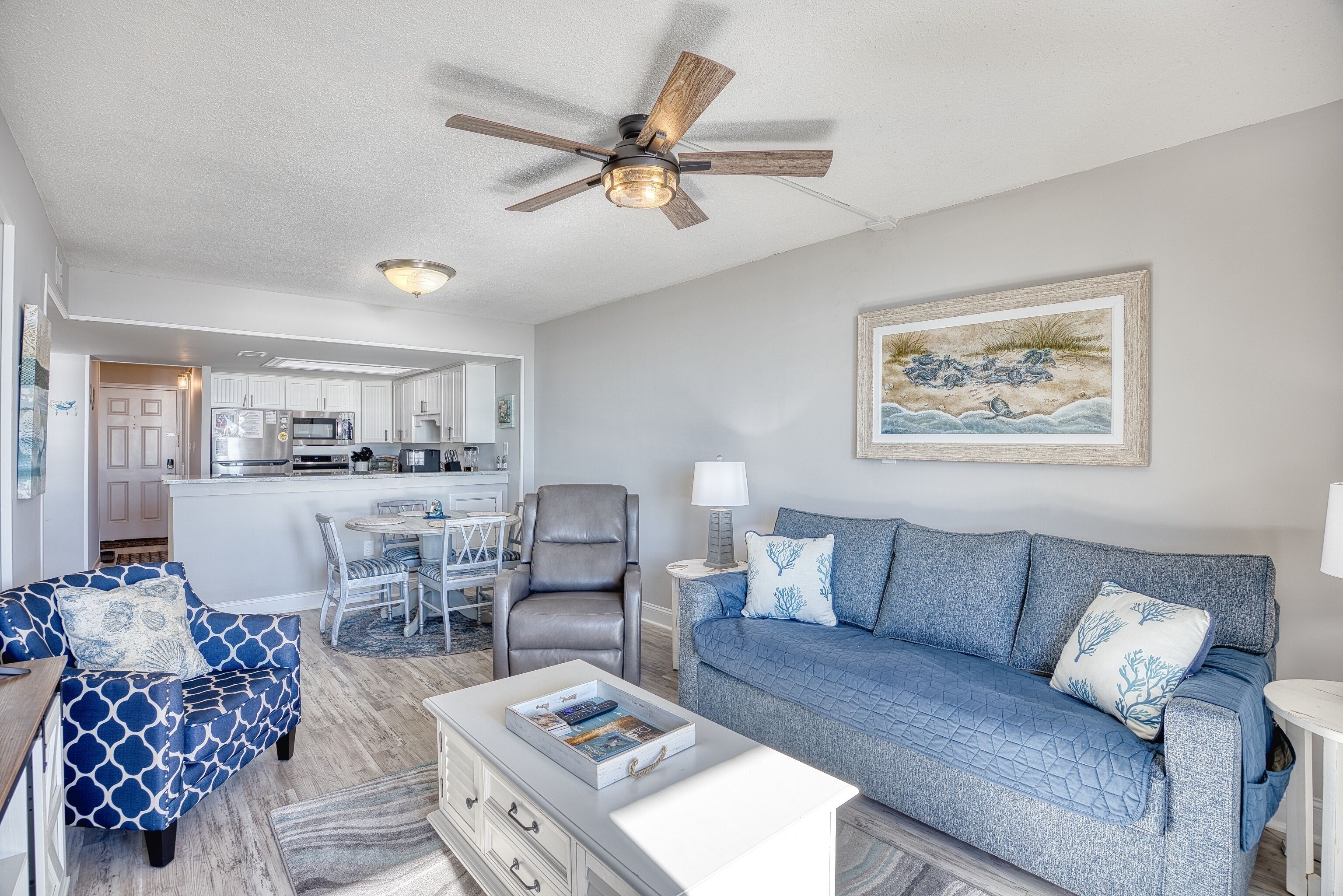 A modern living room with a blue sofa, a patterned armchair, and a white coffee table.