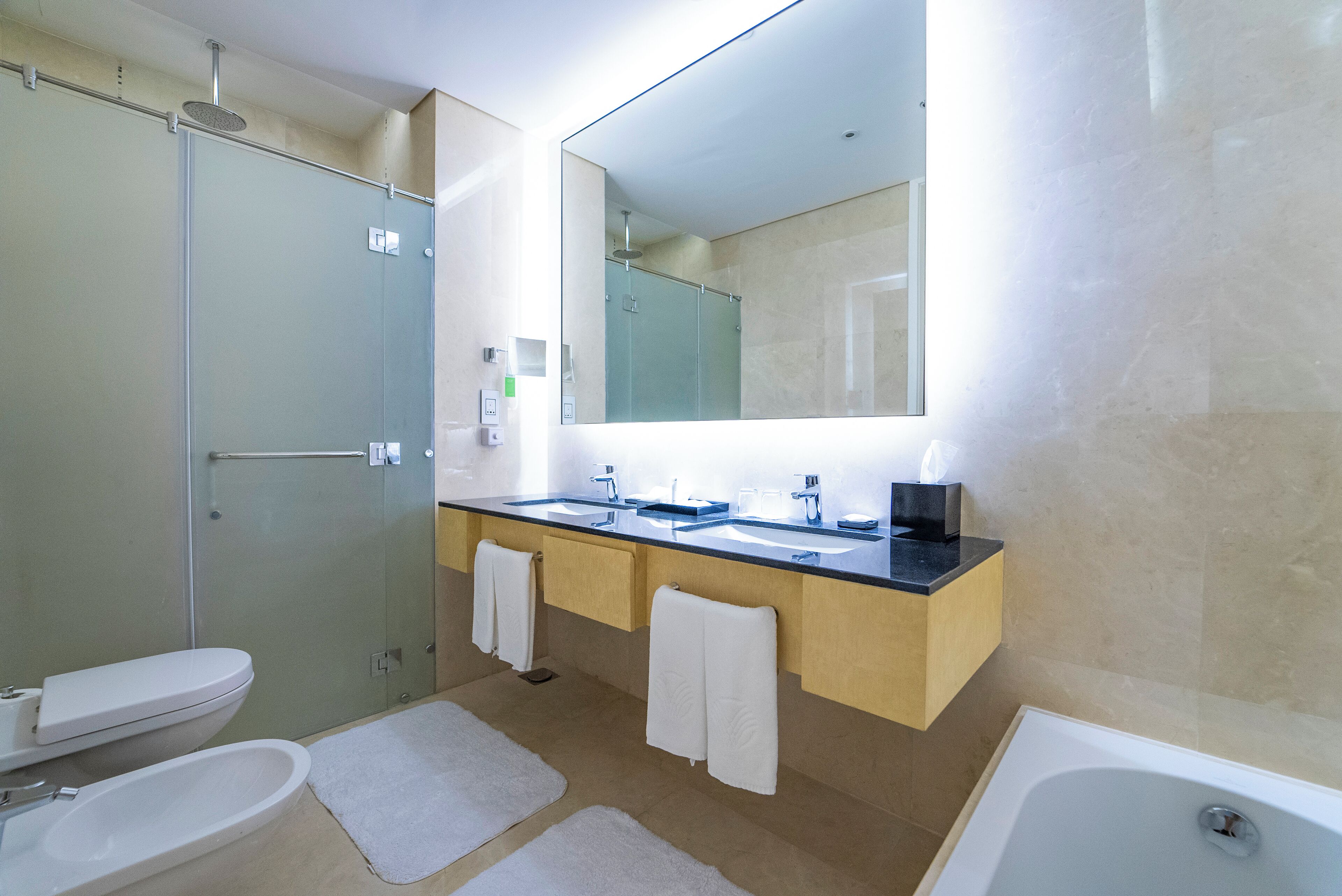 A modern bathroom with a glass shower enclosure, a double sink vanity, and a large mirror.