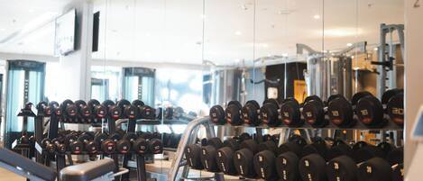 Une salle de sport équipée de divers appareils de musculation, notamment des haltères et des bancs.