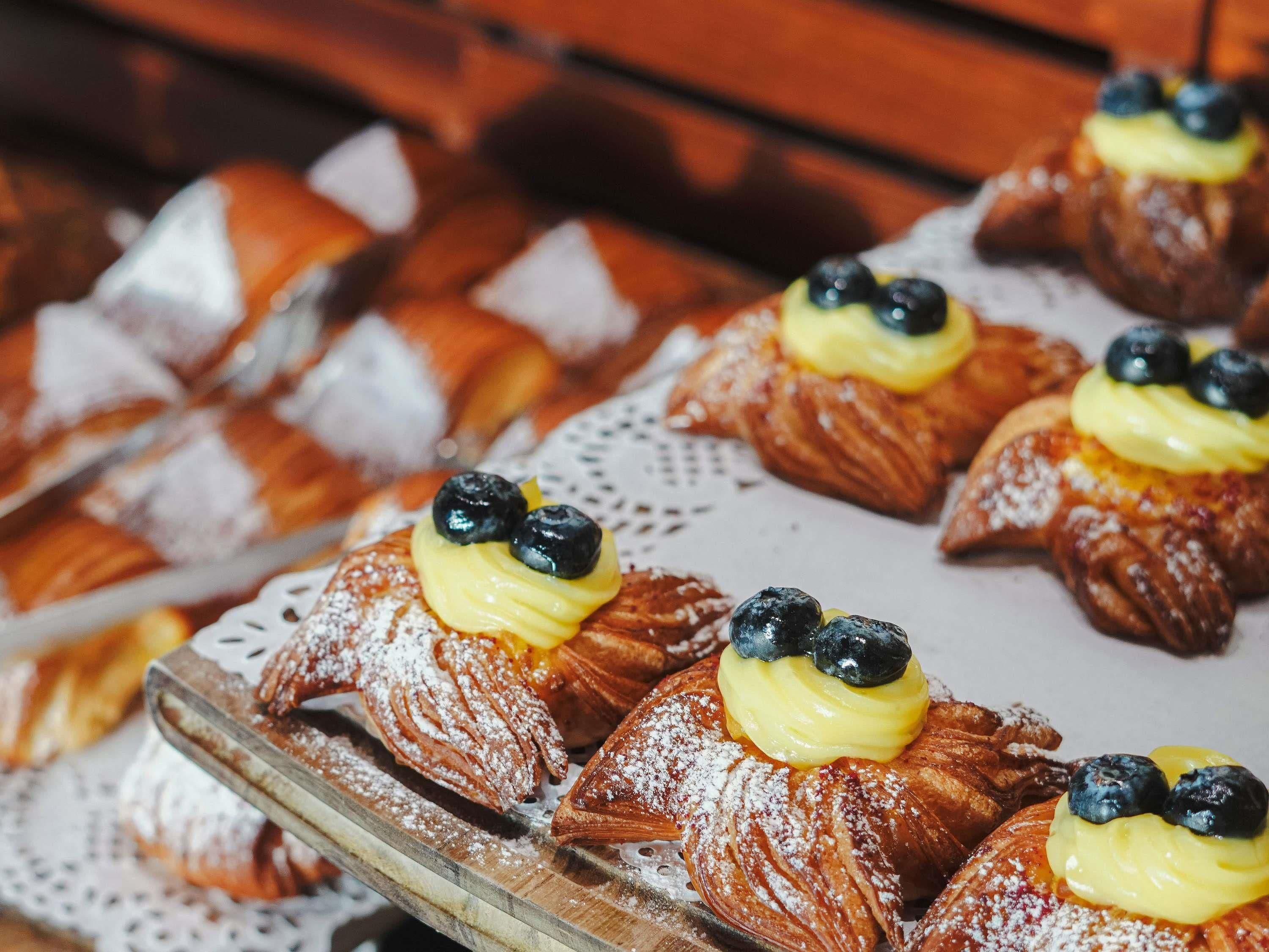 A display of pastries, including croissants and éclairs, arranged on a wooden board.
