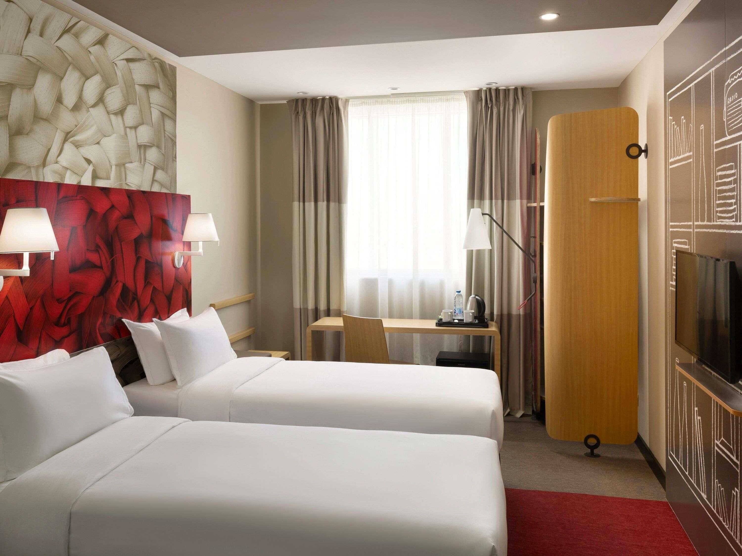 Une chambre d’hôtel avec deux lits, un bureau, une télévision et un mini-bar.