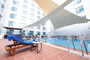 Una piscina al aire libre, sillones reclinables de piscina