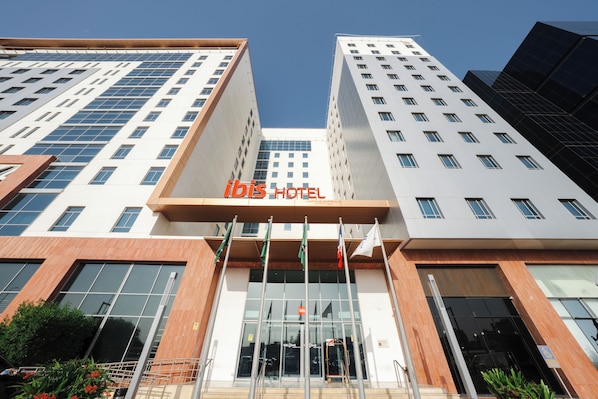 A modern hotel building with a prominent "ibis HOTEL" sign.