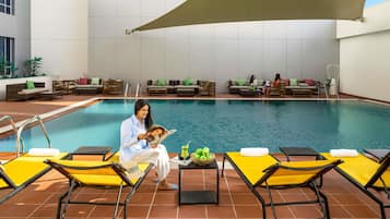 A poolside area with lounge chairs, a pool, and a shaded area.