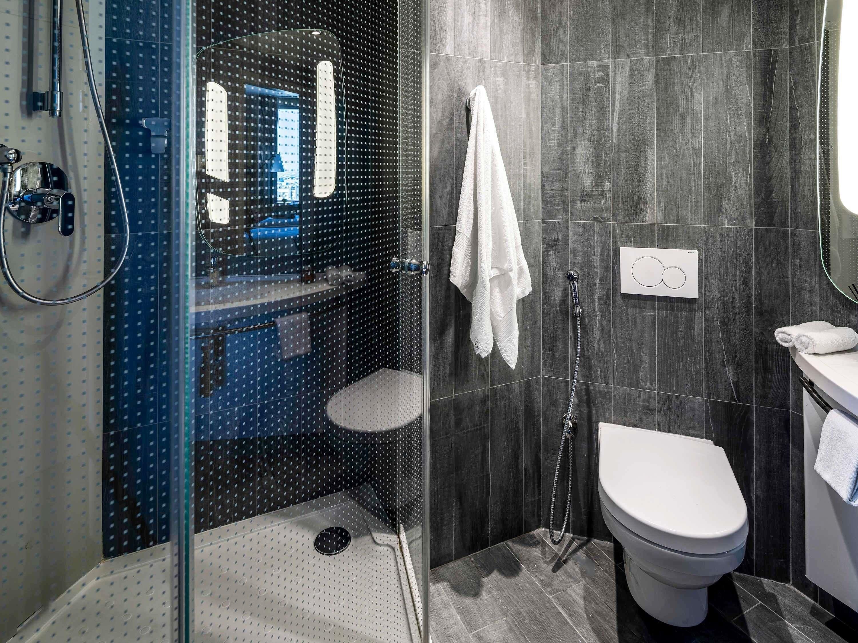 A modern bathroom with a glass shower enclosure, a white toilet, and a towel rack.