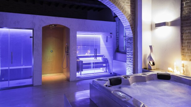 Une salle de spa moderne équipée d’un bain à remous, d’un sauna et d’une table de massage.
