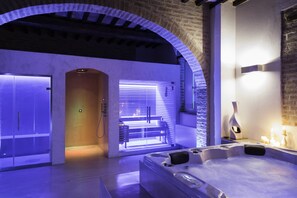 Une salle de spa moderne équipée d’un bain à remous, d’un sauna et d’une table de massage.