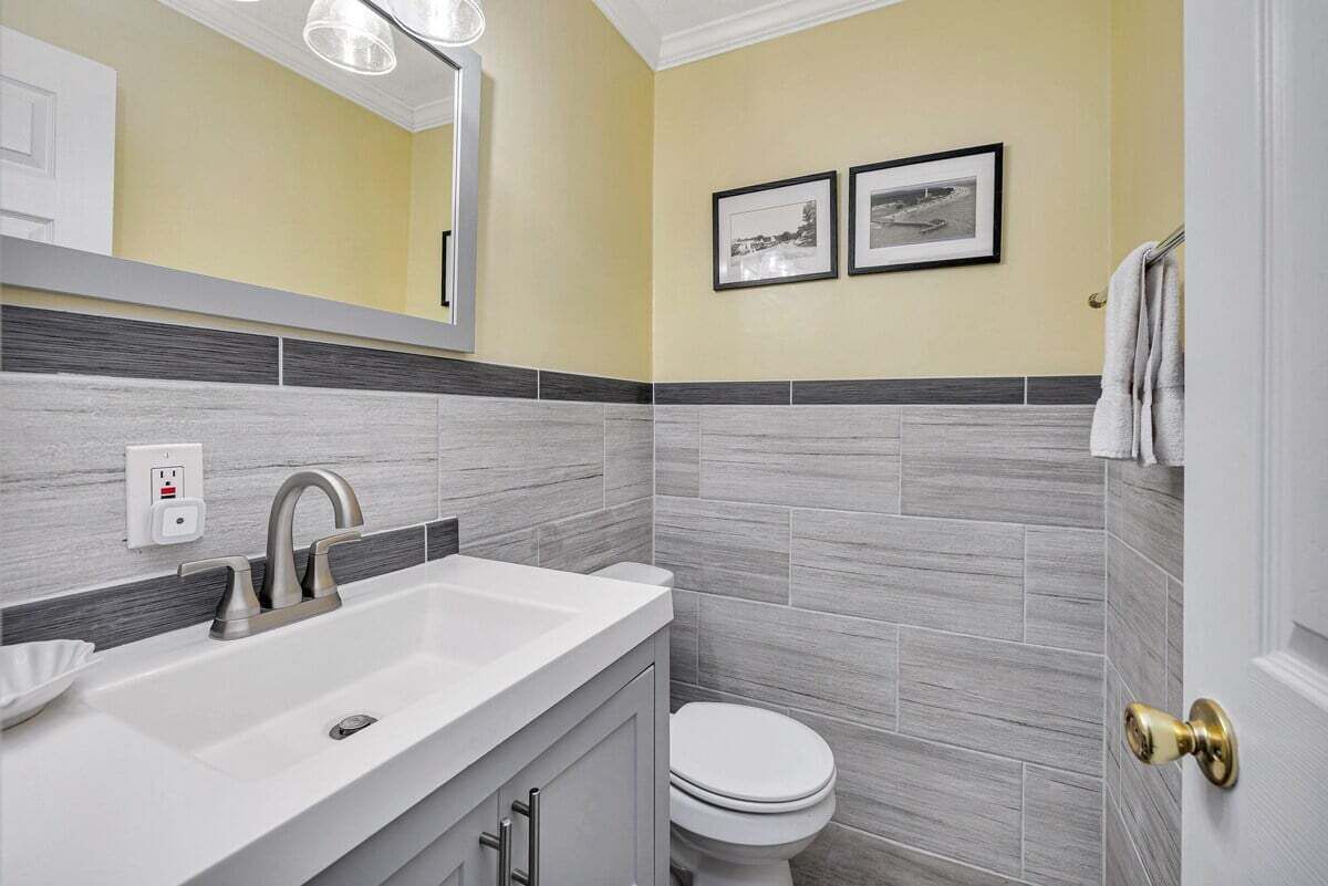 A bathroom with a white sink, a toilet, and a mirror. There are two framed pictures on the wall.