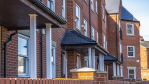 Una hilera de casas de ladrillo rojo con marcos de ventana blancos y techos negros.