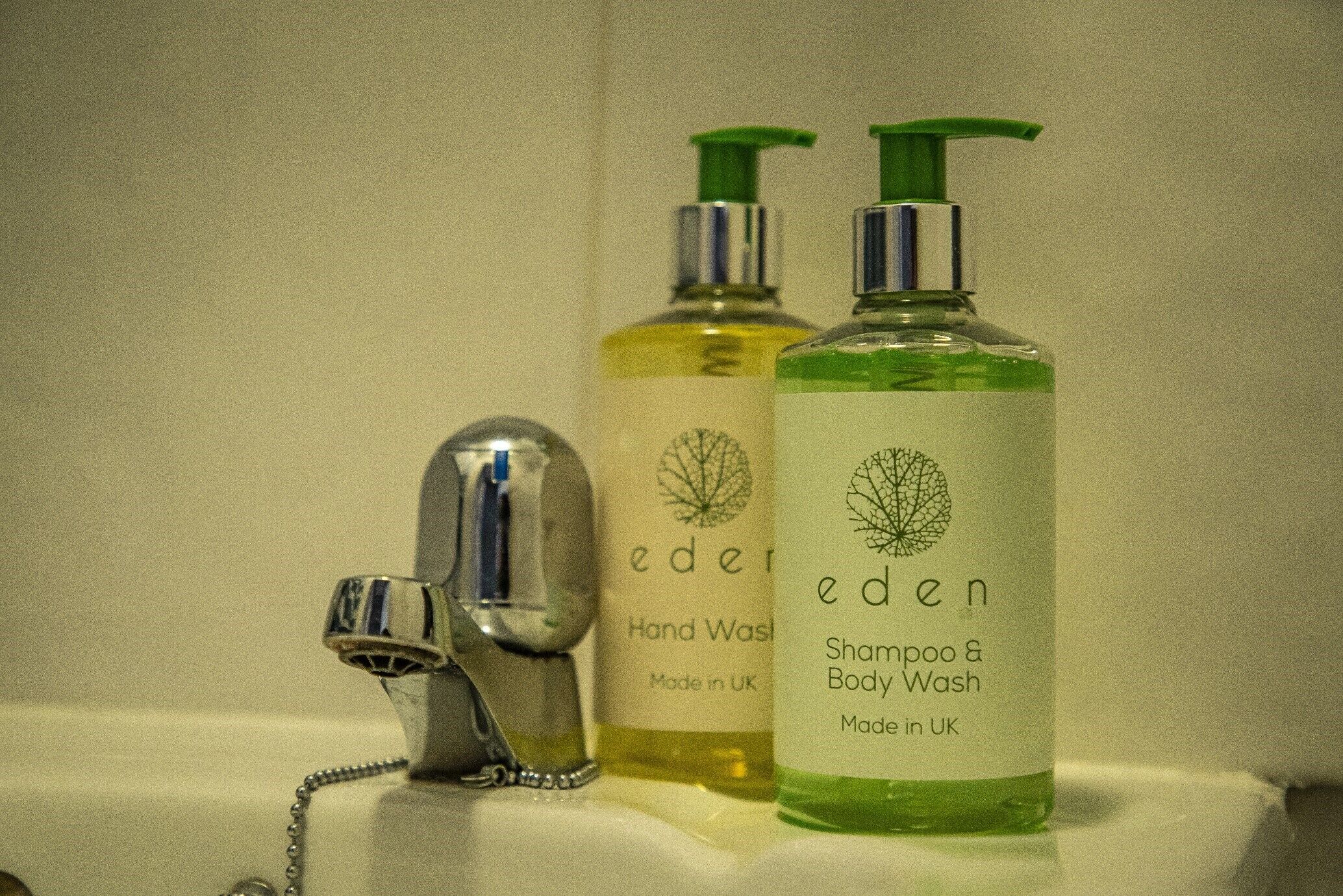 Deux flacons de savon liquide et de shampoing de la marque Eden sont posés sur le lavabo d’une salle de bain.