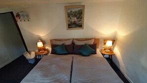 Un lit double avec une literie à rayures, deux tables de chevet avec des lampes, une tête de lit ornée de panneaux à rayures et un tableau encadré accroché au mur.