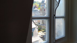 Une fenêtre donnant sur un immeuble avec une tour et une rivière.