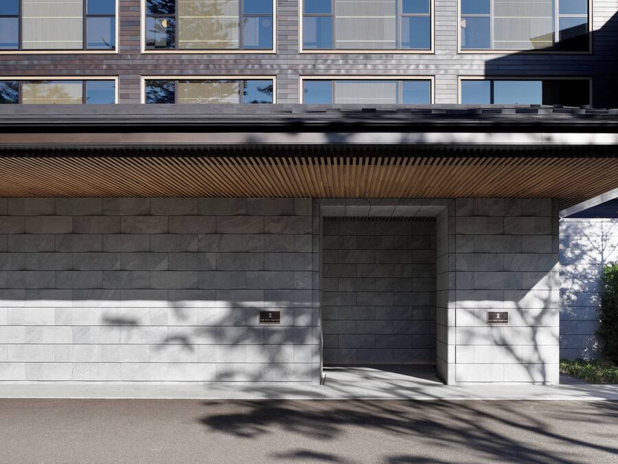 A modern building facade with a flat roof, large windows, and a wooden slatted overhang.