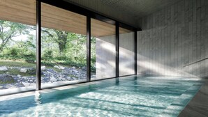 Una piscina interior moderna con grandes ventanales y vistas a un paisaje natural.
