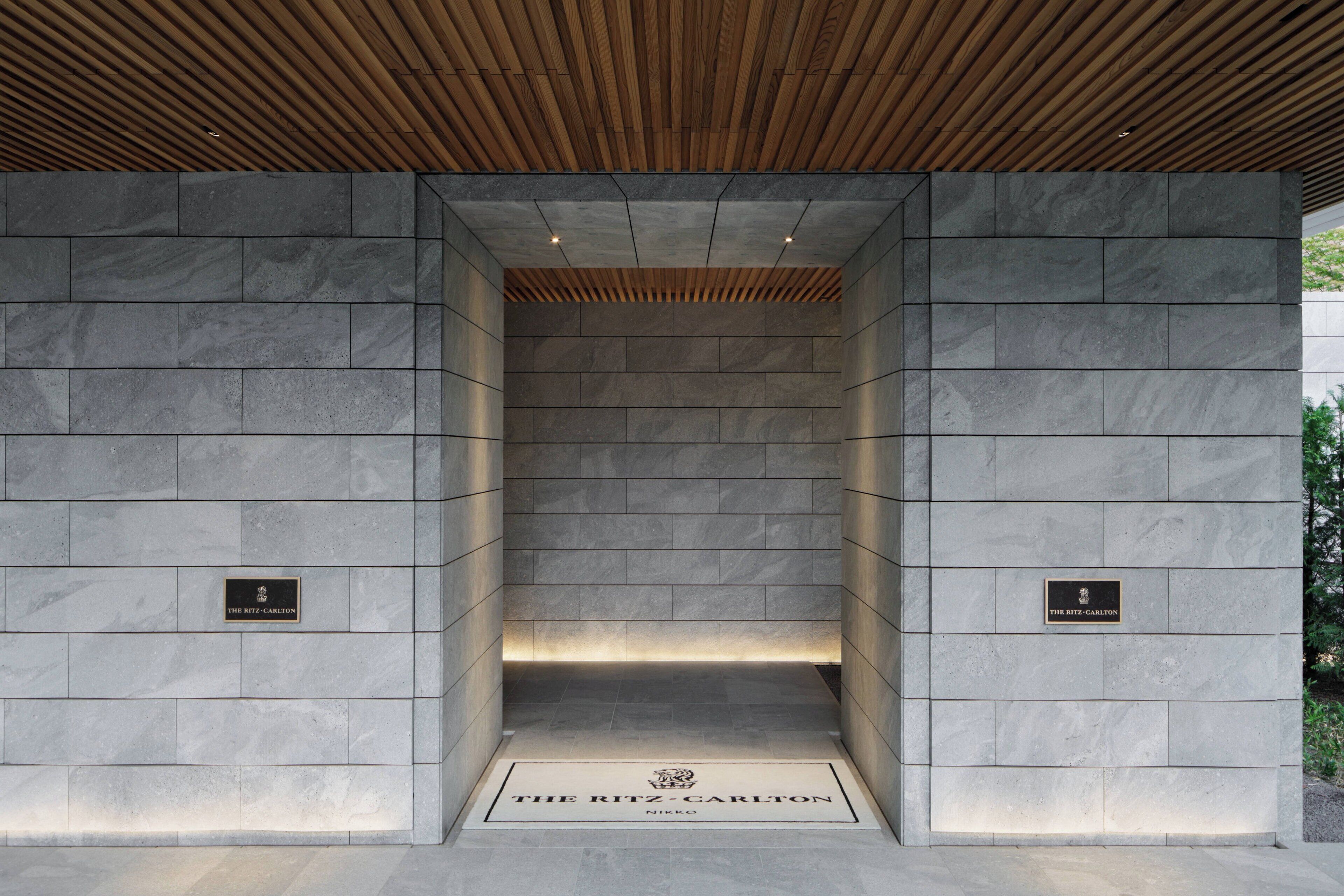 A stone-walled elevator entrance with a plaque reading "The Ritz-Carlton."