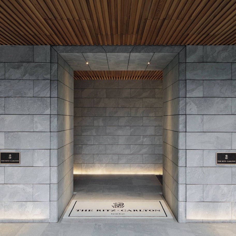 A stone-walled elevator entrance with a plaque reading "The Ritz-Carlton."